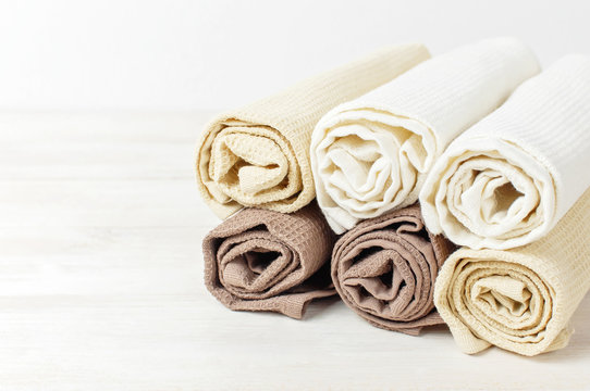 Multicolored clean towels on a light wooden background with copy space. Texture of cotton, waffle towel, textiles. Towels for kitchen or Spa concept.