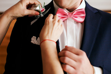 Man groom in a wedding suit at a window with flowers and wedding accessories