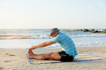Fototapeta na wymiar Fit man stretching outside morning warm-up, view at sea. Fitness and sport concept