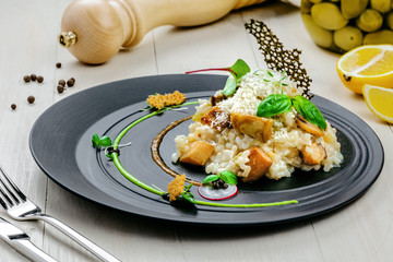 Delicious Italian risotto with porcini mushrooms and parmesan cheese on a wooden table. Classic Italian cuisine food. Close-up shot.