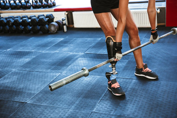 Strong disabled sports woman make sport exercises with barbell equipment in gym.