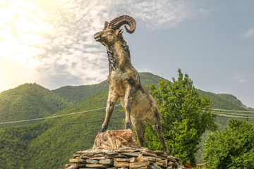 Ram statue with mountain landscape background.