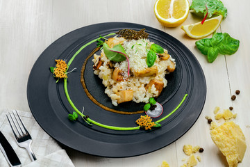 Creamy baked mushroom risotto from Italy on an exclusive beautiful plate. Vegetarian Italian meal made of rice, vegetable broth, porcini mushrooms and parmesan cheese. Top view shot.