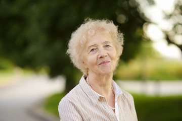 Outdoor portrait of beautiful senior woman with curly white hair