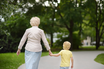 Fototapeta premium Beautiful granny and her little grandson walking together in park