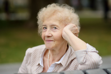 Outdoor portrait of beautiful senior woman with curly white hair