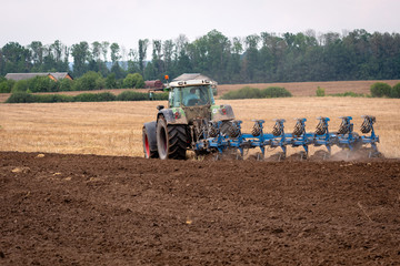 A tractor with a plow treats the soil. View from the back.