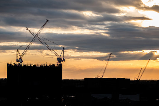 Silhouette Crane and building At Construction Site During Sunset.