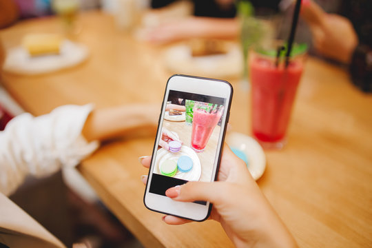 Young woman blogger is making mobile food photo. Concept content for instagram