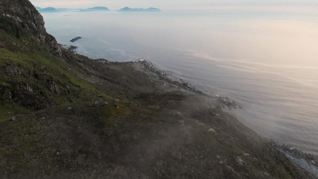 Soaring over rugged oceanfront mountains at dawn in Alnes, Norway