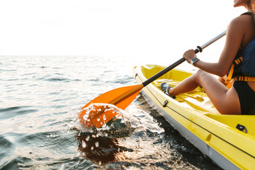 Young woman kayaking on lake sea in boat.