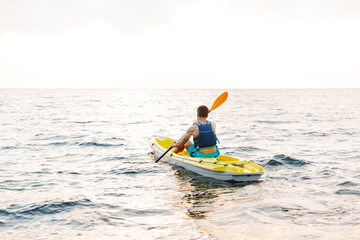 Fototapeta na wymiar Handsome man kayaking on lake sea in boat.