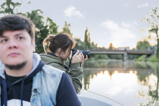 Woman with a camera takes pictures of the nature from the boat, sailing along the river