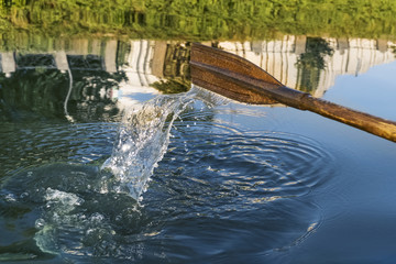 Old wooden oar rowed on the water near the shore of the city embankment