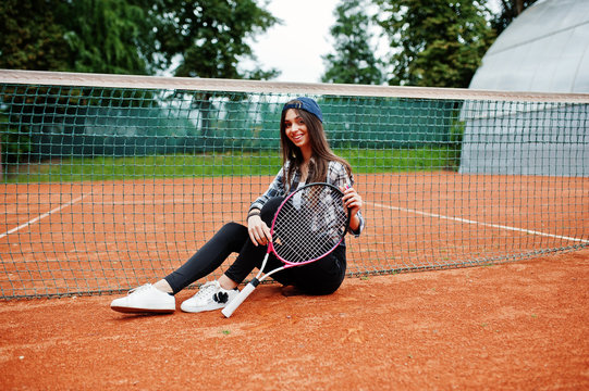 Young sporty girl player with tennis racket on tennis court.