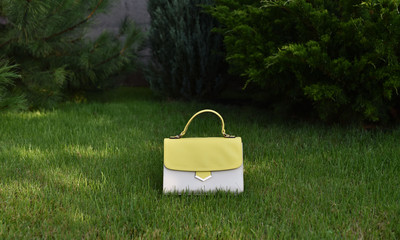 front view of yellow and beige women handbag on green grass