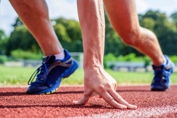 Runner ready to go close up. Ready steady go concept. At beginning of great sport career. Hand touch track path close up. Hand of sportsman on running track low start position. Starting point