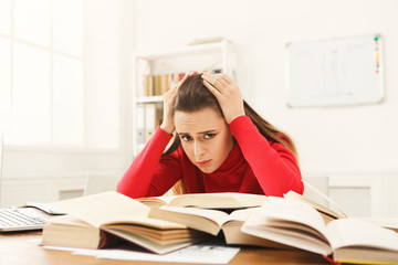 Student girl studying at table full of books