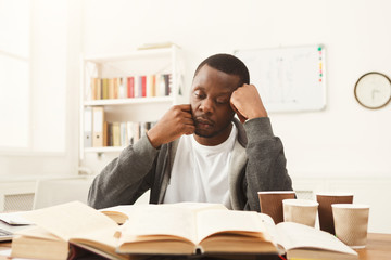 Black male student studying at table full of books
