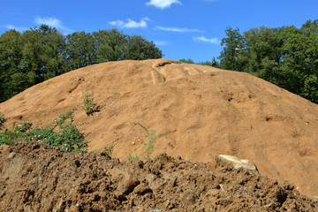 Large pile of sand on a wasteland near the city park
