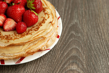 Pancakes with strawberries close-up. Maslenitsa. Thin freshly baked pancakes with strawberries. Dessert in the form of pancakes on a saucer.