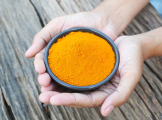 Turmeric powder in hand on old wooden table. Herbs