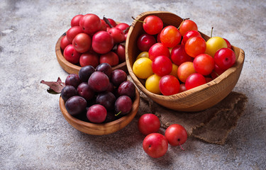 Various type of cherry-plum in wooden bowls 