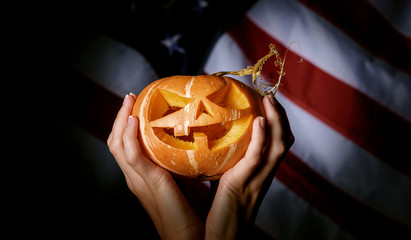 pumpkin halloween in hand against the background of the American flag