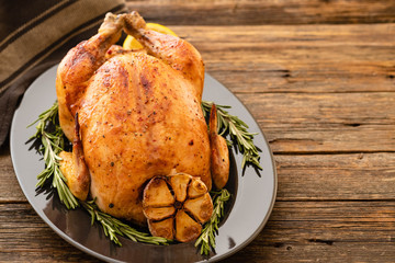 Whole roasted chicken with lemon and rosemary on a black plate. Rustic style. Christmas concept. Christmas turkey. Top view.