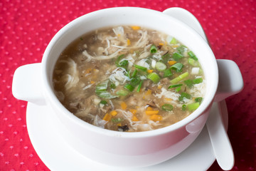 Traditional Chinese soup with beef and vegetables West Lake Beef in a white plate on a red background. Shallow depth of field.