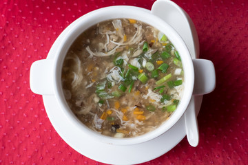 Traditional Chinese soup with beef and vegetables West Lake Beef in a white plate on a red background. top view. Shallow depth of field.