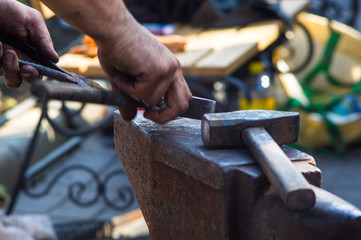 blacksmith performs the forging of hot glowing metal on the anvil