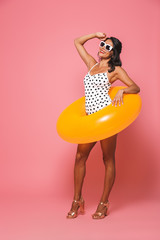 Woman in swimwear with beach rubber ring looking aside.
