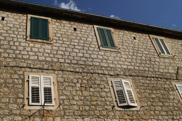 Old traditional building with white and green wooden window covers