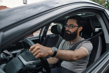 Modern casual bearded man driving a car