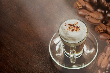 Hot mocha coffee with milk foam and cocoa powder on a wooden table and coffee beans placed on the table.. wooden table.Copyspace