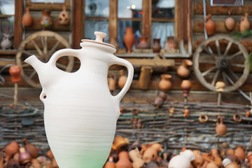 Ceramic white jug on the background of an old wooden house.