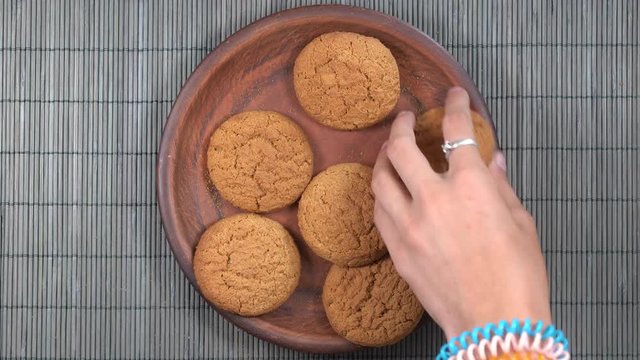 Plate full of oatmeal cookies being snatched up by five hungry children.  Close up, top view, macro