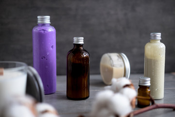 Bottles with natural spa cosmetic products on dark gray concrete table. Beauty blogger, salon treatments, minimalism concept