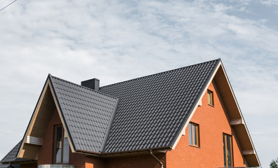 Modern roof covered with tile effect PVC coated brown metal roof sheets. - obrazy, fototapety, plakaty