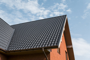 Modern roof covered with tile effect PVC coated brown metal roof sheets.