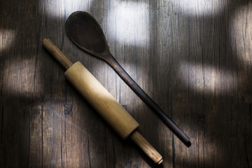 wooden spoon and roll of pasta on top of wooden table, photographed from top to bottom