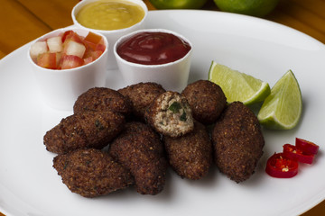 Traditional arabic food, kibes served on white plate accompanied by salad, ketchup, mustard and...