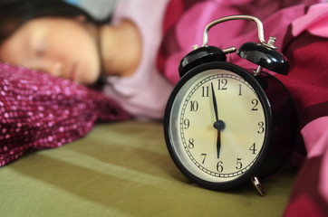 Sleeping child in bed and alarm clock