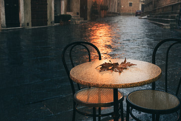 Parisian cafe terrace in rainy autumn day. Rain drops and maple leaf on the table. - 217885071