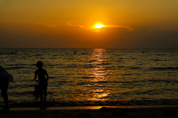 silhouette woman run away from kid to beach and sunset