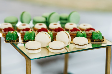 Obraz na płótnie Canvas White macaroons served with green sweets on a candy bar