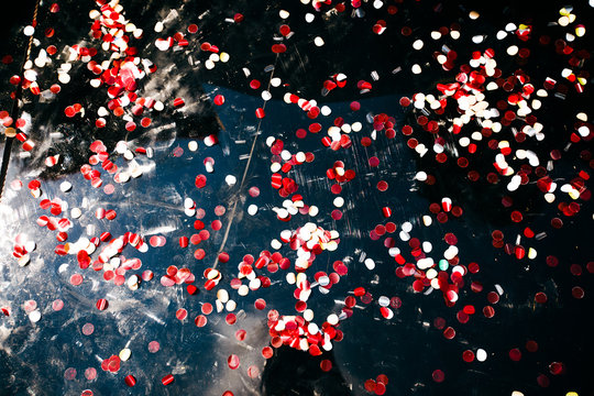 Red and white confetti lies on black car's hood