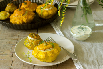 Pattypan squash or pumpkins stuffed with ricotta with basil and dill and served with sour cream sauce. Vegetarian food.