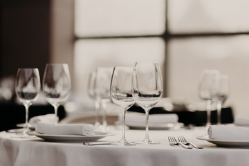 Catering and celebration concept. Festive served dinner table with glasses and cutlery on white tablewear in luxury banquet with no people. Table setting